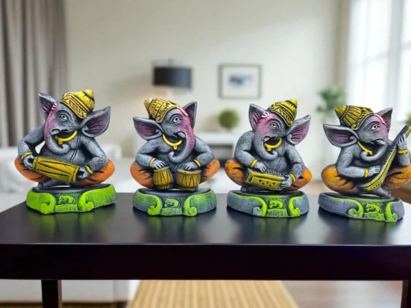 Handmade multicolor grey-toned burnt clay Ganesha musician figurines set of four, with yellow and orange accents, displayed on a dark table in a modern living room background.