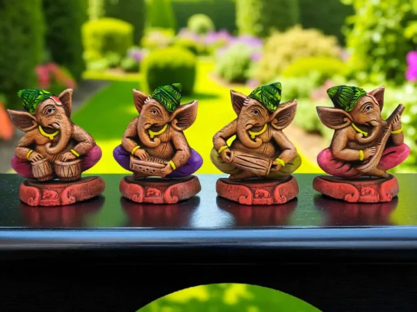 Handmade multicolor burnt clay Ganesha musician figurines set of four, displayed on a black surface with a garden background.