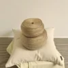 Two large rolls of natural jute twine placed on a cream-colored cushion and folded fabric against a neutral background.