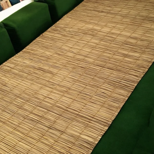 Natural handmade river grass mat laid across a green cushioned sofa — 3x7 ft eco-friendly mat used for indoor seating or sofa covering.