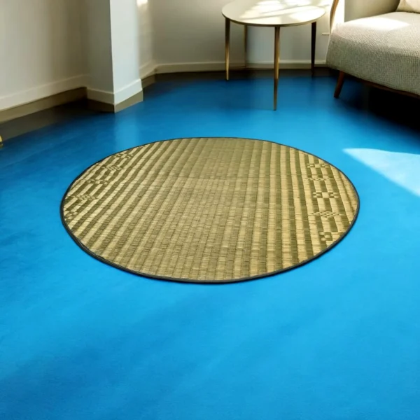 4ft round river grass (Madurkathi) rug on a bright blue floor near a modern sofa and side table in a sunlit room