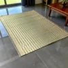 Handwoven double-layer Korai grass mat placed in a modern indoor living room with grey flooring and wooden furniture