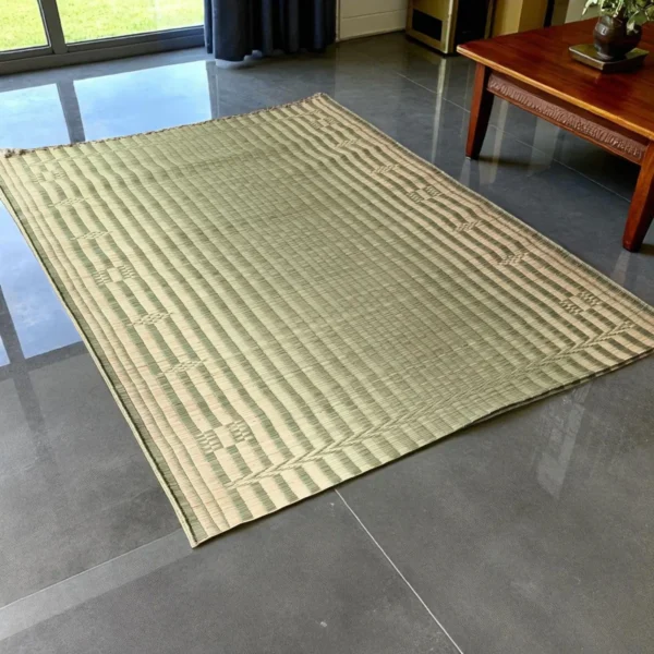 Handwoven double-layer Korai grass mat placed in a modern indoor living room with grey flooring and wooden furniture