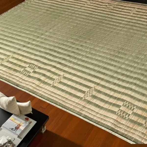 Close-up of a 60x74 inch handwoven Korai grass mat on polished wooden flooring beside a coffee table