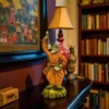 aul Man Clay Statue with Ektara placed on a wooden shelf in a traditional Indian home interior with books and folk painting in the background