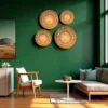 Four handwoven bamboo wall baskets arranged on a dark green wall in a modern living room with wooden furniture and sunlight