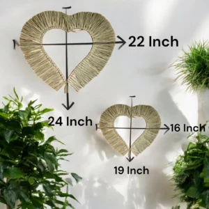 Two handmade heart-shaped natural grass straw wall hangings in 24x22 inch and 19x16 inch sizes, displayed on a white wall with green plants around.