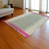 Natural Madurkathi grass mat with red and pink ethnic border spread in a cozy living room setting