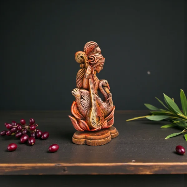 Handcrafted clay Goddess Saraswati idol holding a veena with a swan, placed on a wooden surface against a dark background with natural elements.