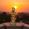 Handmade burnt clay Maa Durga terracotta idol placed outdoors with a beautiful sunset in the background.