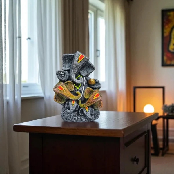 Handmade burnt clay Lord Ganesha statue in black terracotta finish with painted details, placed on a wooden table in a softly lit modern room.