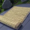 Handwoven natural Kusha grass mat placed outdoors on a stone path – eco-friendly handmade mat for puja, yoga, and meditation.