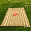 Handwoven Korai Grass Mat placed on green grass outdoors with a folded orange cloth on top