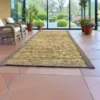 Natural handwoven Kusha grass mat placed indoors on a tiled floor near wicker chairs and potted plants – eco-friendly mat for puja, yoga, and meditation.