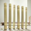 Rolled handmade reed grass (Madurkathi) mats standing upright in a minimal room – eco-friendly natural floor and yoga mats.