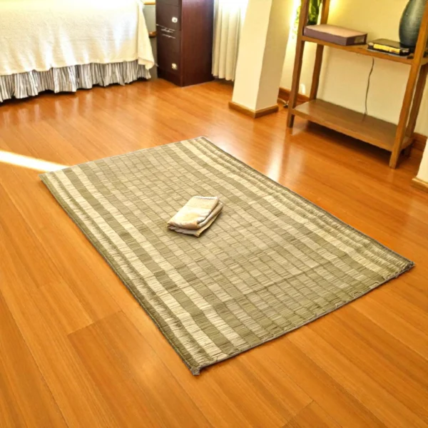 Handwoven Korai Grass Mat placed on a wooden floor in a bedroom with a folded cloth on top