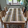 Handwoven black and natural-striped grass table mats with a matching long table runner arranged neatly on a wooden dining table in a bright dining room.