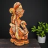 Handcrafted terracotta Goddess Saraswati statue holding a veena, seated with a swan, placed on a wooden surface against a dark background.
