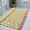 Handwoven Madurkathi korai grass floor mat in natural beige with traditional woven border, rolled partially for indoor home décor use