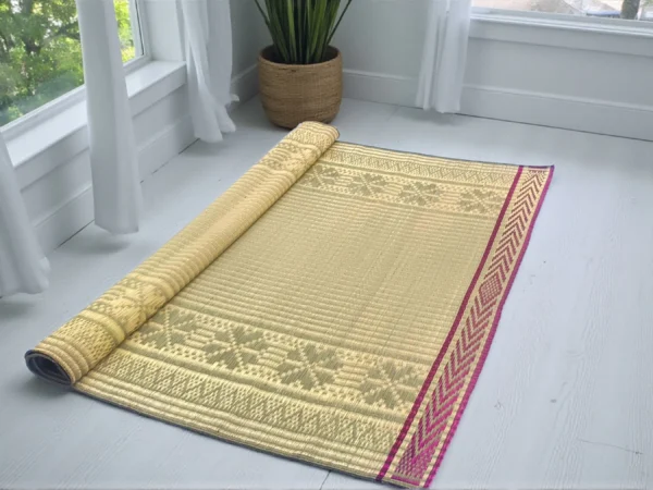 Handwoven Madurkathi korai grass floor mat in natural beige with traditional woven border, rolled partially for indoor home décor use