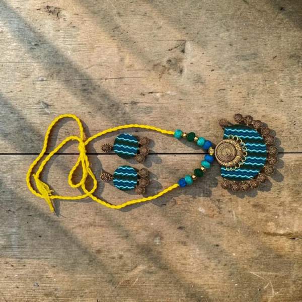 Handmade terracotta necklace set with teal striped pendant and matching earrings, yellow thread cord design on rustic wooden background