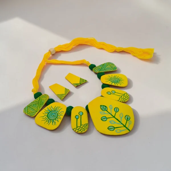 Handmade yellow tribal fabric necklace set with matching earrings on white background, boho statement jewelry with hand-painted design