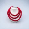 Handmade red fabric bead multi-layer necklace displayed on white stand minimal background