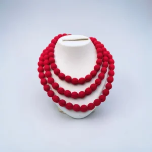Handmade red fabric bead multi-layer necklace displayed on white stand minimal background