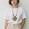 Woman wearing handmade terracotta necklace set with floral pendant and matching earrings, styled with white t-shirt and neutral pants in minimalist background