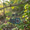 handmade blue floral terracotta necklace and earrings set hanging on tree branch with natural green background