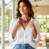 Woman wearing handmade fabric necklace set with pink and purple panels, oxidized silver charms, and matching earrings styled with a white shirt and casual outfit.