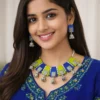 Woman wearing handmade fabric necklace set with blue and green panels, oxidized silver charms, and matching jhumka earrings with ethnic kurti.