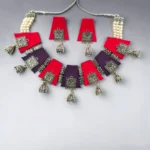 Handmade fabric necklace set with red and purple panels, oxidized silver charms, pearl thread detailing, and matching jhumka earrings.