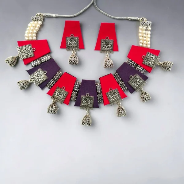 Handmade fabric necklace set with red and purple panels, oxidized silver charms, pearl thread detailing, and matching jhumka earrings.
